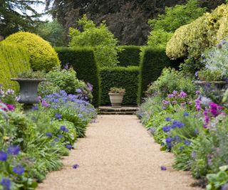 Pathway leading through old fashioned garden borders