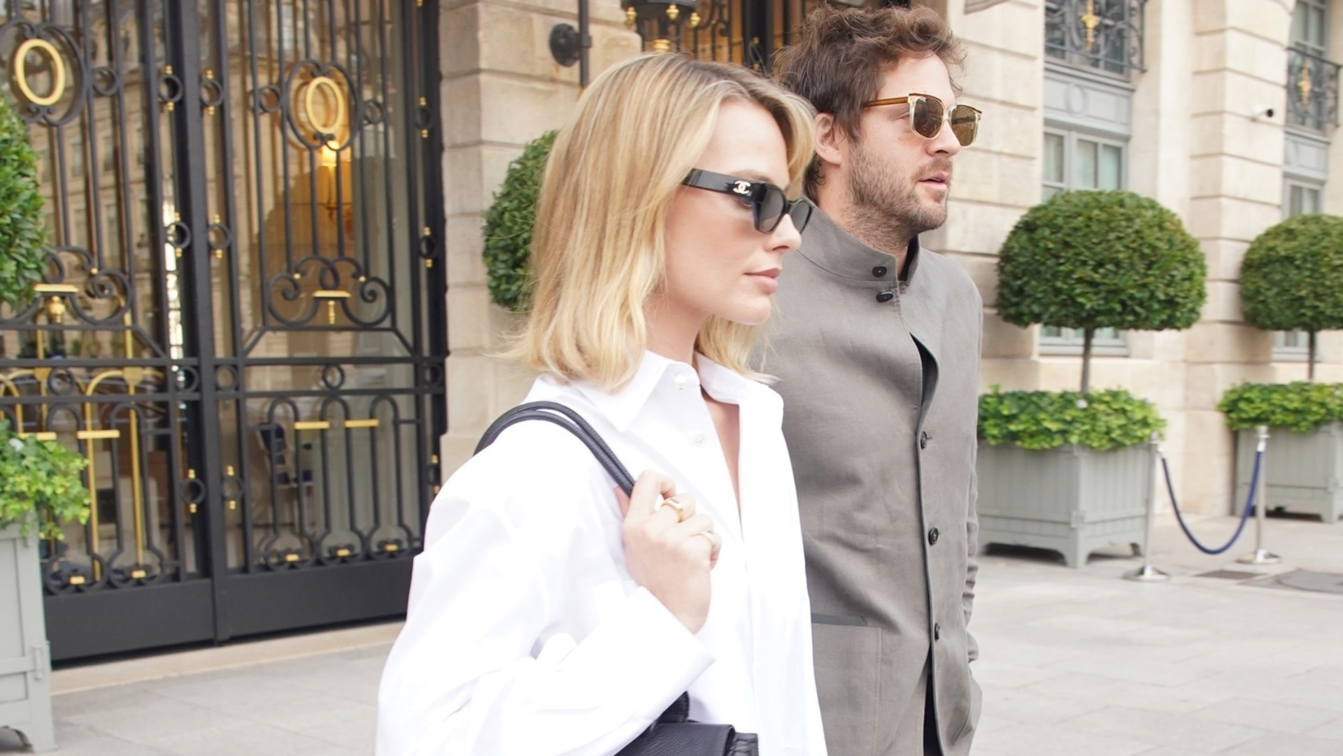 Margot Robbie wearing a white button-down, light-wash jeans, and black pumps, leaving The Ritz in Paris