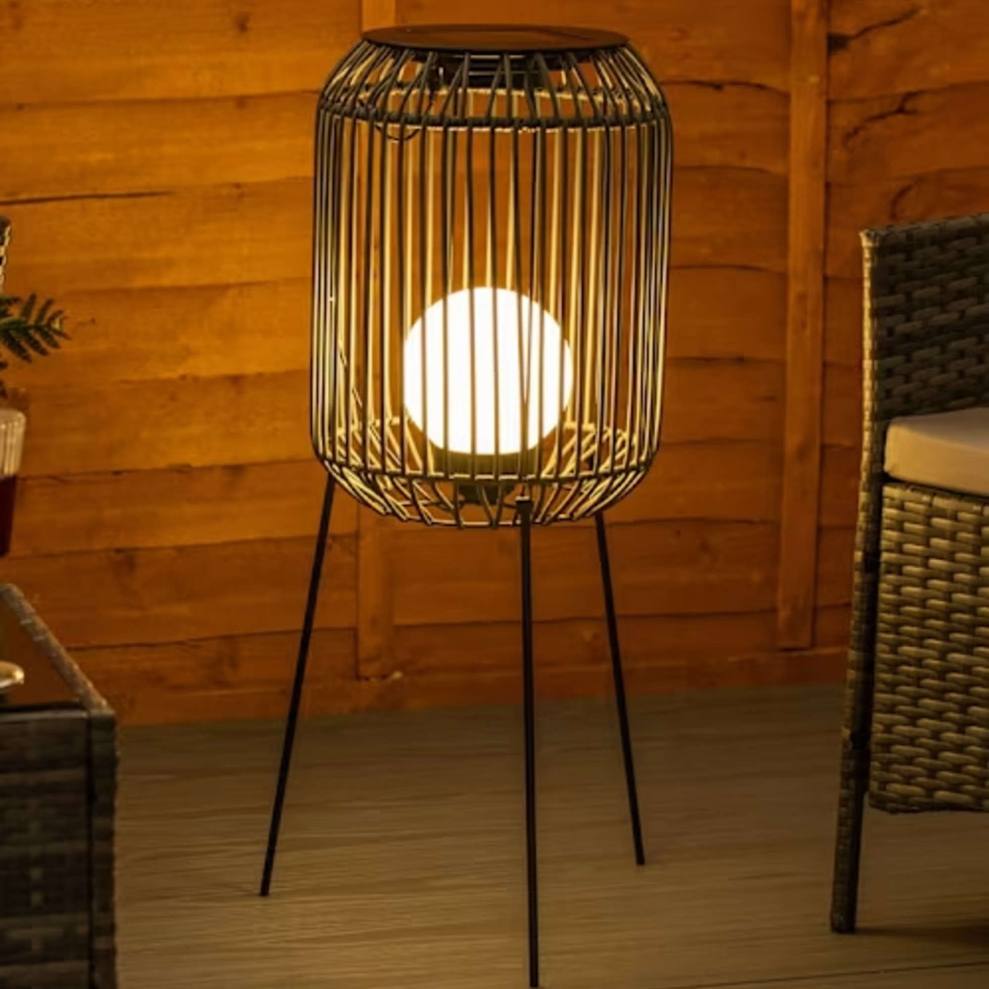 Turned on ValueLights Solar Rattan Tripod Floor Lamp on a patio in the dark