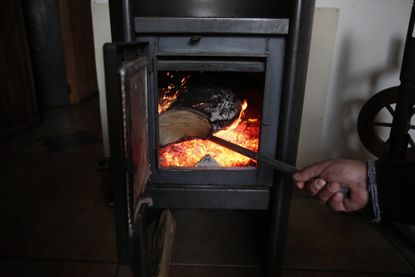 A man adds firewood into a wood burning stove in Temuco, about 680 km south of Santiago, Chile on June 22, 2019. - The indiscriminate use of firewood to heat up and combat the cold of the sou