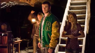 chris hemsworth in a lettermans jacket and two other young people in a basement in cabin in the woods