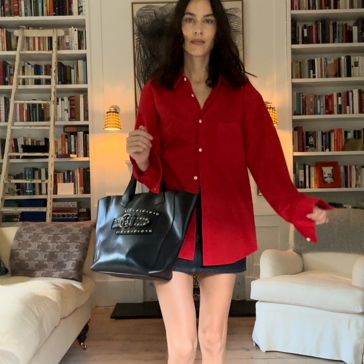 Alexa wears a red button-down shirt, mini skirt, and black tote bag.