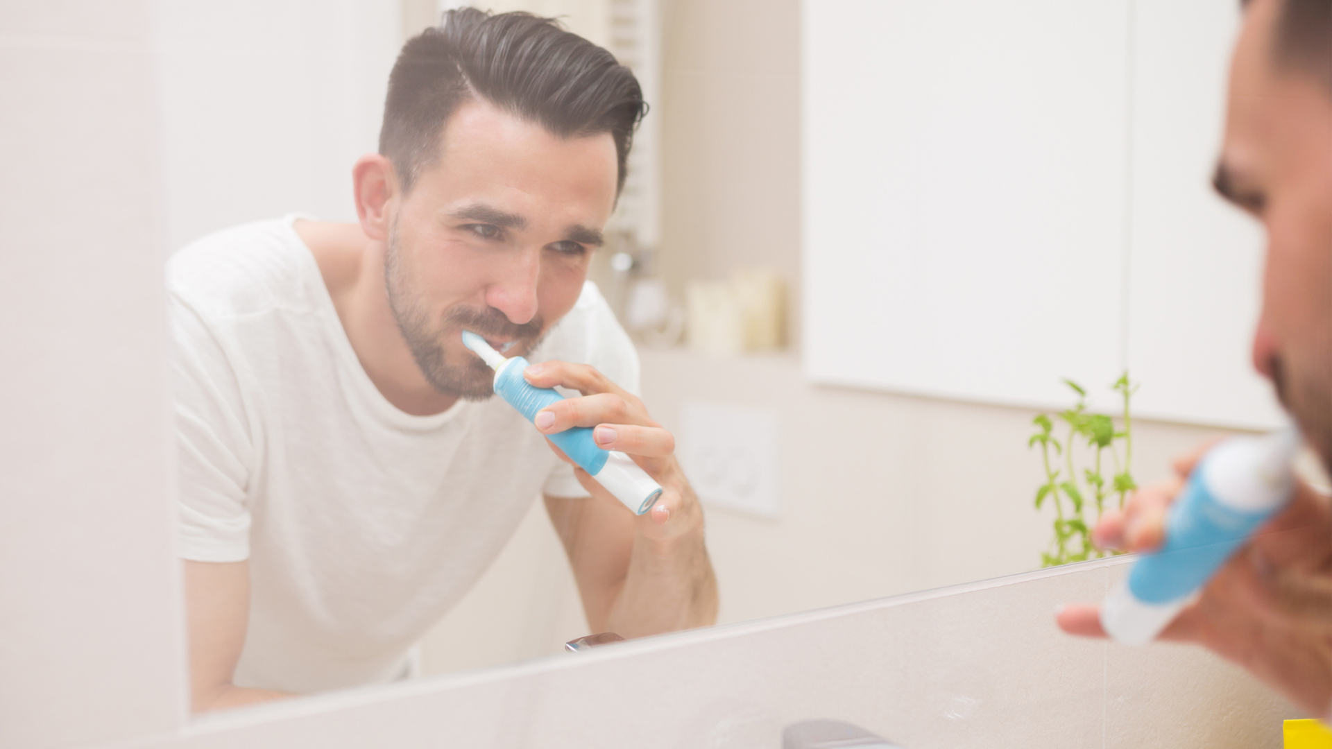 image shows a man brushing his teeth in the mirror