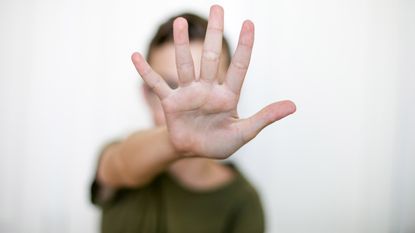 A woman holds up her outstretched hand in a "No!" gesture.