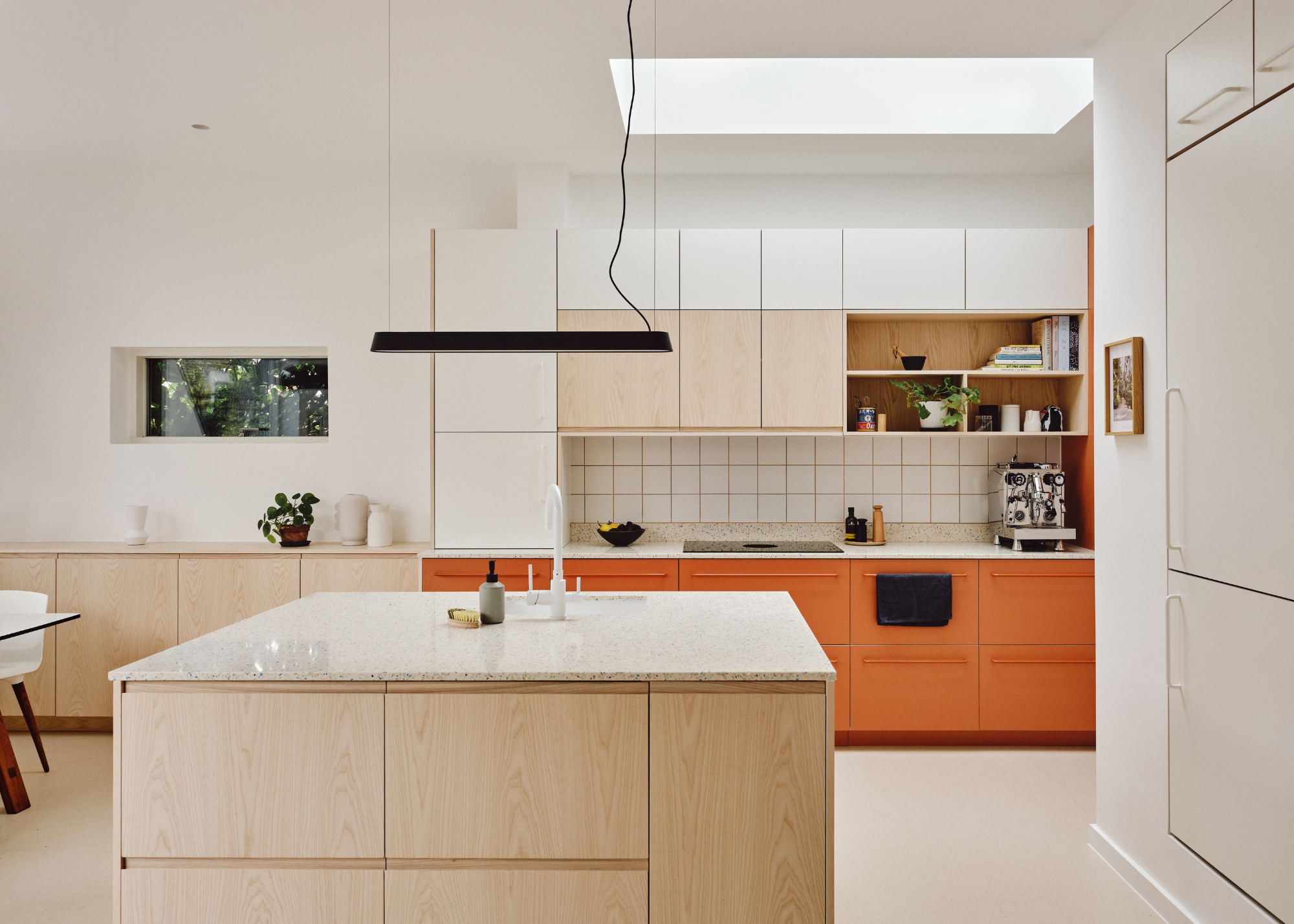 A minimalist timber and orange kitchen with white countertops and white walls