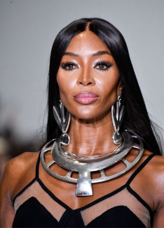 Supermodel Naomi Campbell on the catwalk wearing a designer black gown and striking metal jewellery