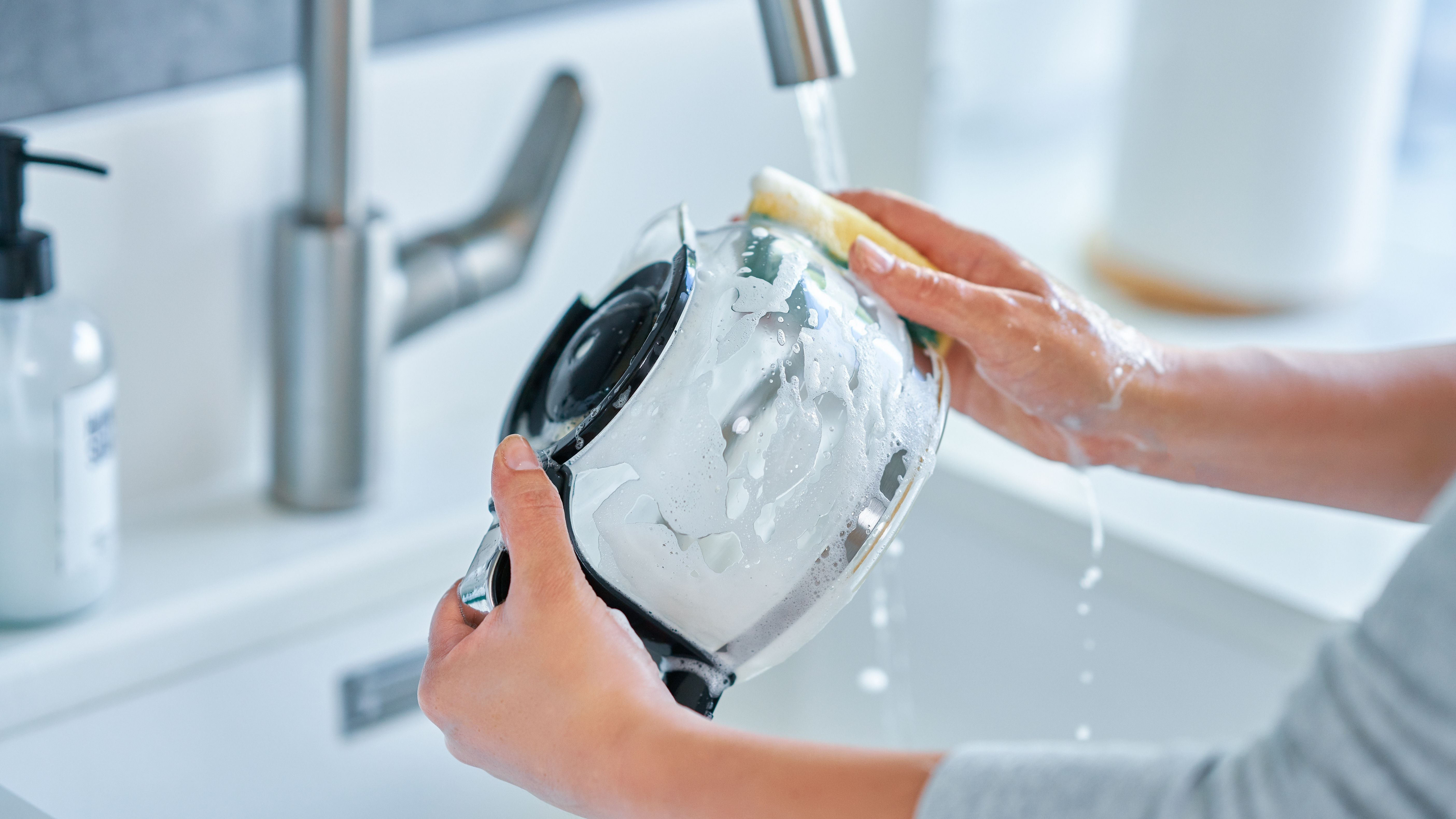 a photo of a woman cleaning a drip coffee machine carafe