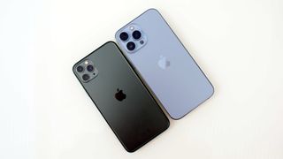 En svart och en blå iPhone 13 Pro Max som ligger med baksidorna vända uppåt. Visas mot en vit bakgrund.