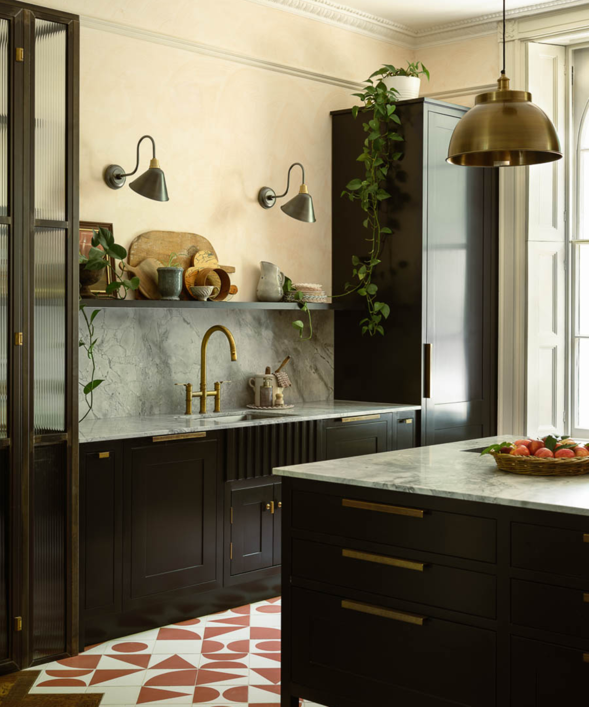 kitchen with black units, terracotta and white geometric floor tiles, brass pendant light and pewter swan necked wall lights