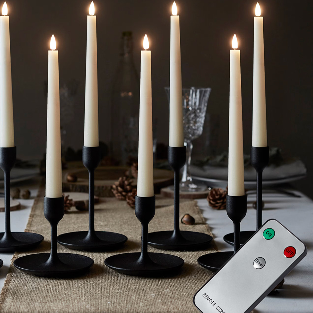 Tapered LED candles in black metal candle holders on a table with a hessian table runner with a remote control