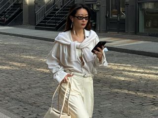 Woman walks down the street in NY in an all white outfit and Alaia Le Teckel Bag.