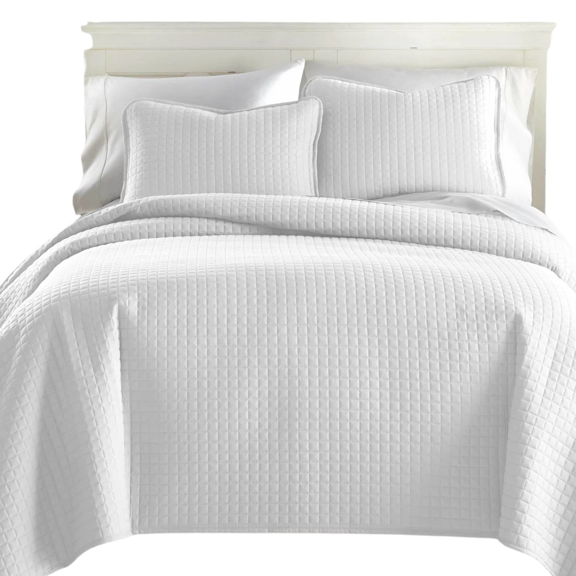 White summer bedding and pillows on a bed with a white headboard
