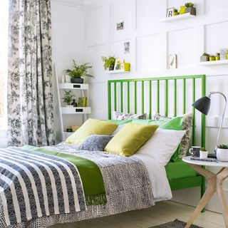 White bedroom with green bed, wall panelling and black details