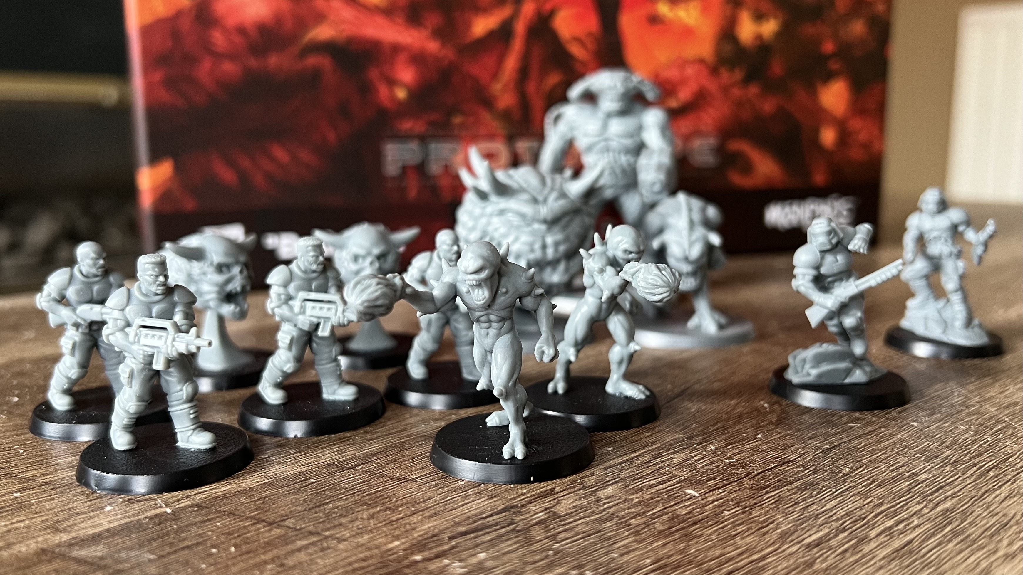 Demon and Doom Guy miniatures in front of Doom Arena Board Game box