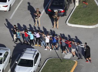 Students are guided by the police to exit the Marjory Stoneman Douglas High School