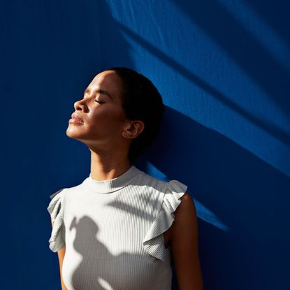 Trauma responses: A woman facing away against a blue wall