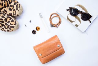 White background with shoes, purse, earrings, sunglasses and a bracelet on it