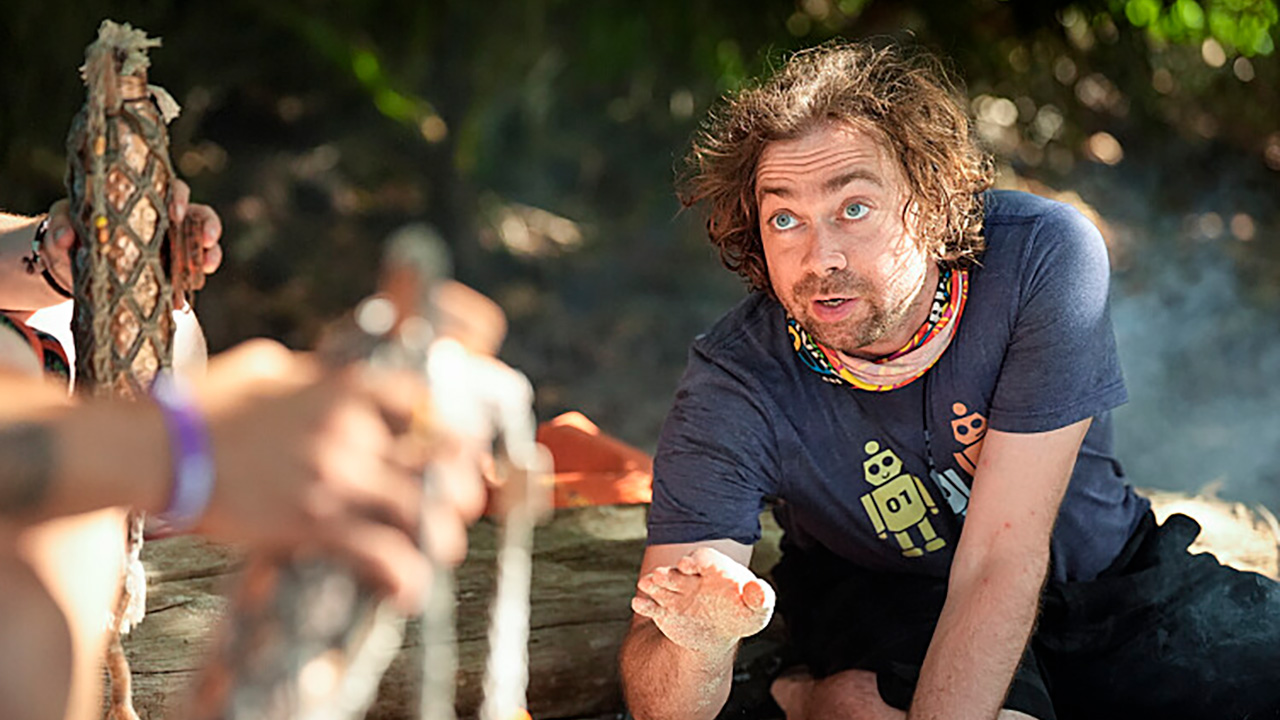 Christian Hubicki sitting while talking to a tribe castmate during Survivor 50.