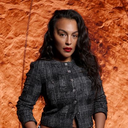 Paloma Elsesser wearing red lipstick with a wavy hairstyle. 