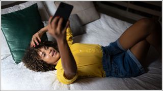 Young woman lying in bed doing a video call or taking a selfie at home