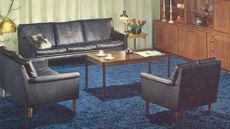 Vintage IKEA living room with blue carpet, black leather sofas and a wooden wall of storage