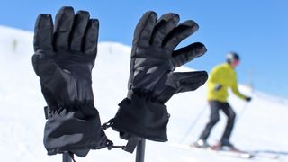 Ski gloves on poles with a skier in the background