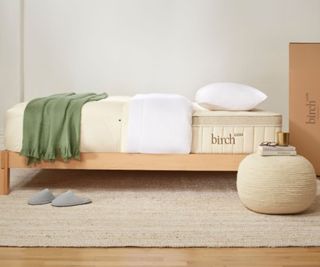 Sheets and a pillow on the Birch Luxe Natural Mattress against a white wall.