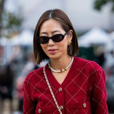 Aimee Song wears red blazer, skirt, bag, black sandals, necklace, sunglasses outside Chanel during the Womenswear Spring/Summer 2024 as part of Paris Fashion Week on October 03, 2023 in Paris, France