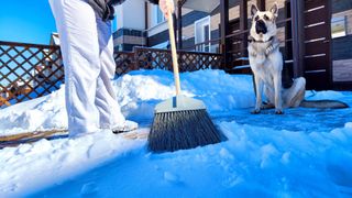 Woman using broom to clear snow