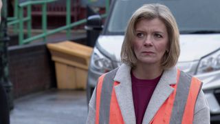 Leanne wears a high vis vest and looks annoyed