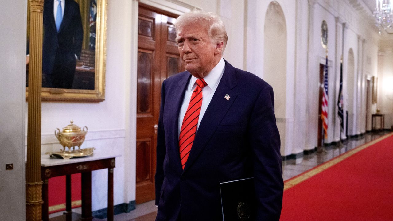 Trump strolling down a hallway in the White House with a folder under his arm