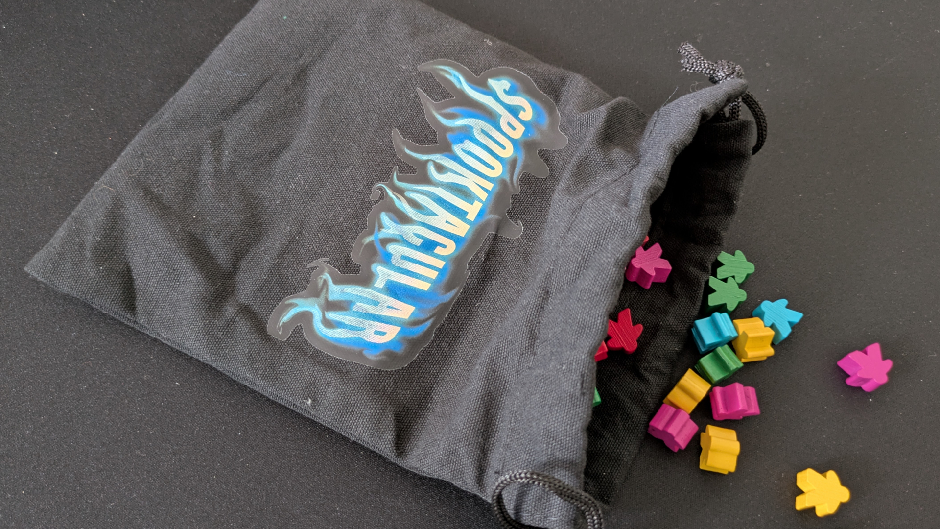 Open Spooktacular bag spilling colorful meeple tokens onto a black surface