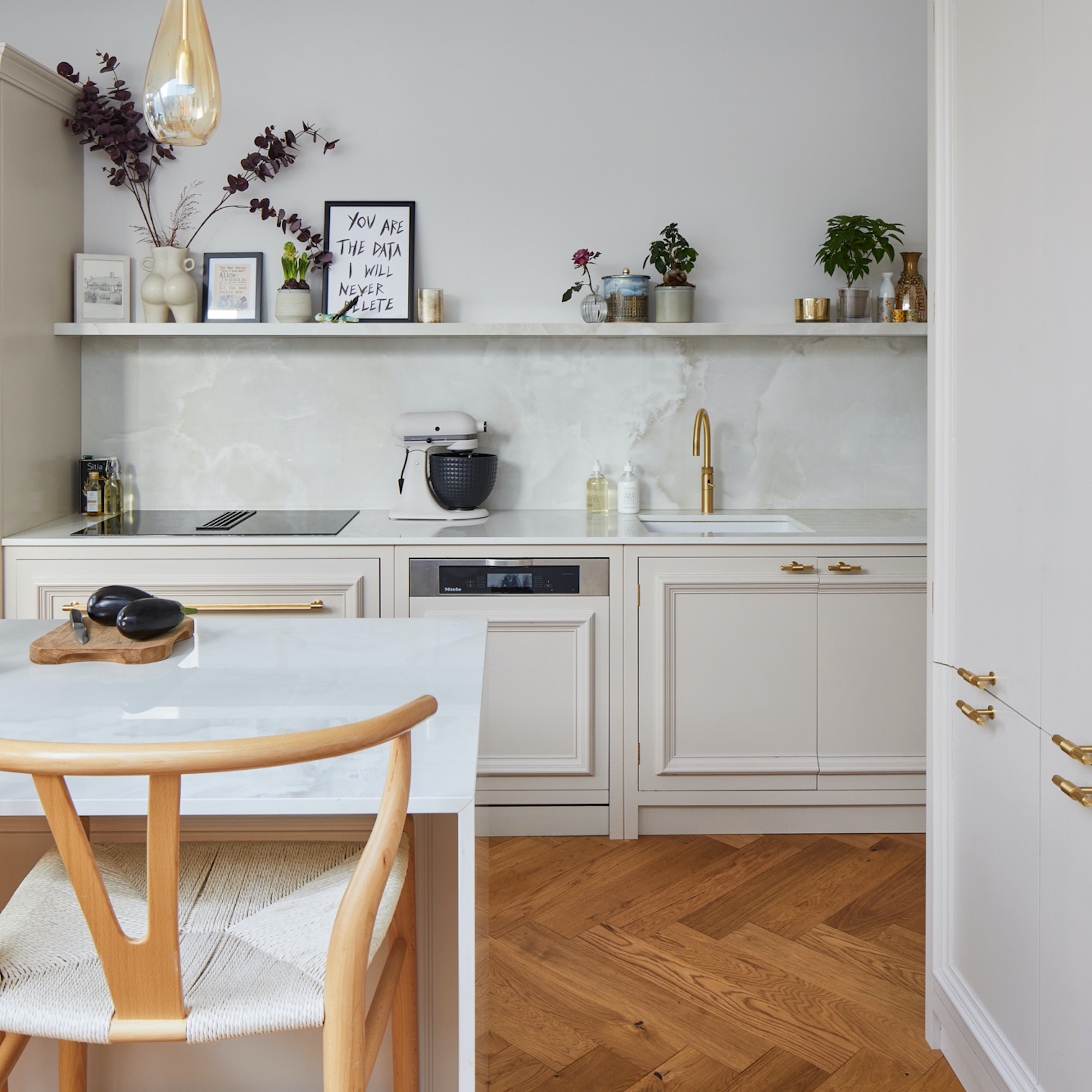 white kitchen with open shelves and brass handles and wood flooring