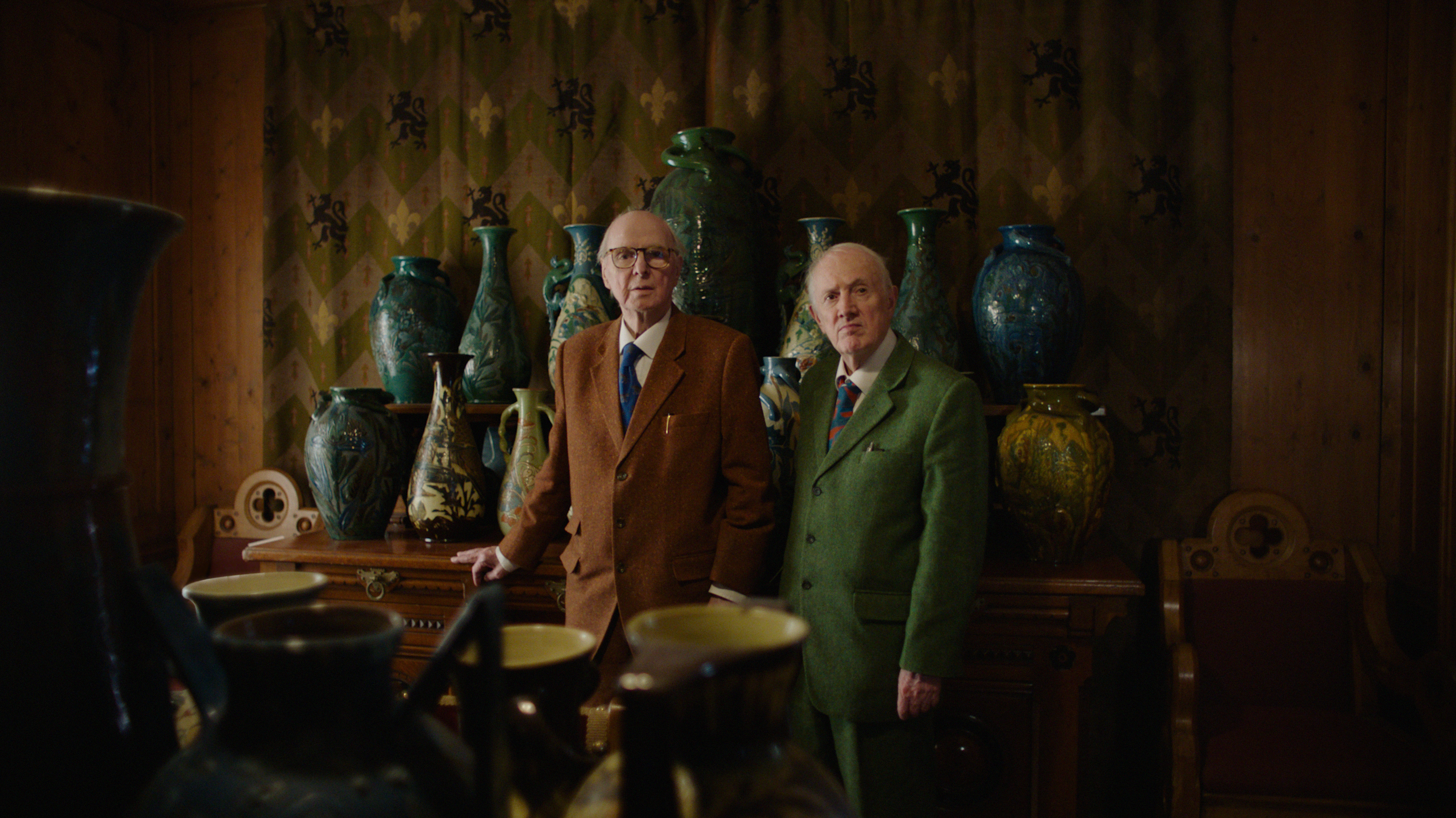 Gilbert &amp; George stand in front of a line of vases