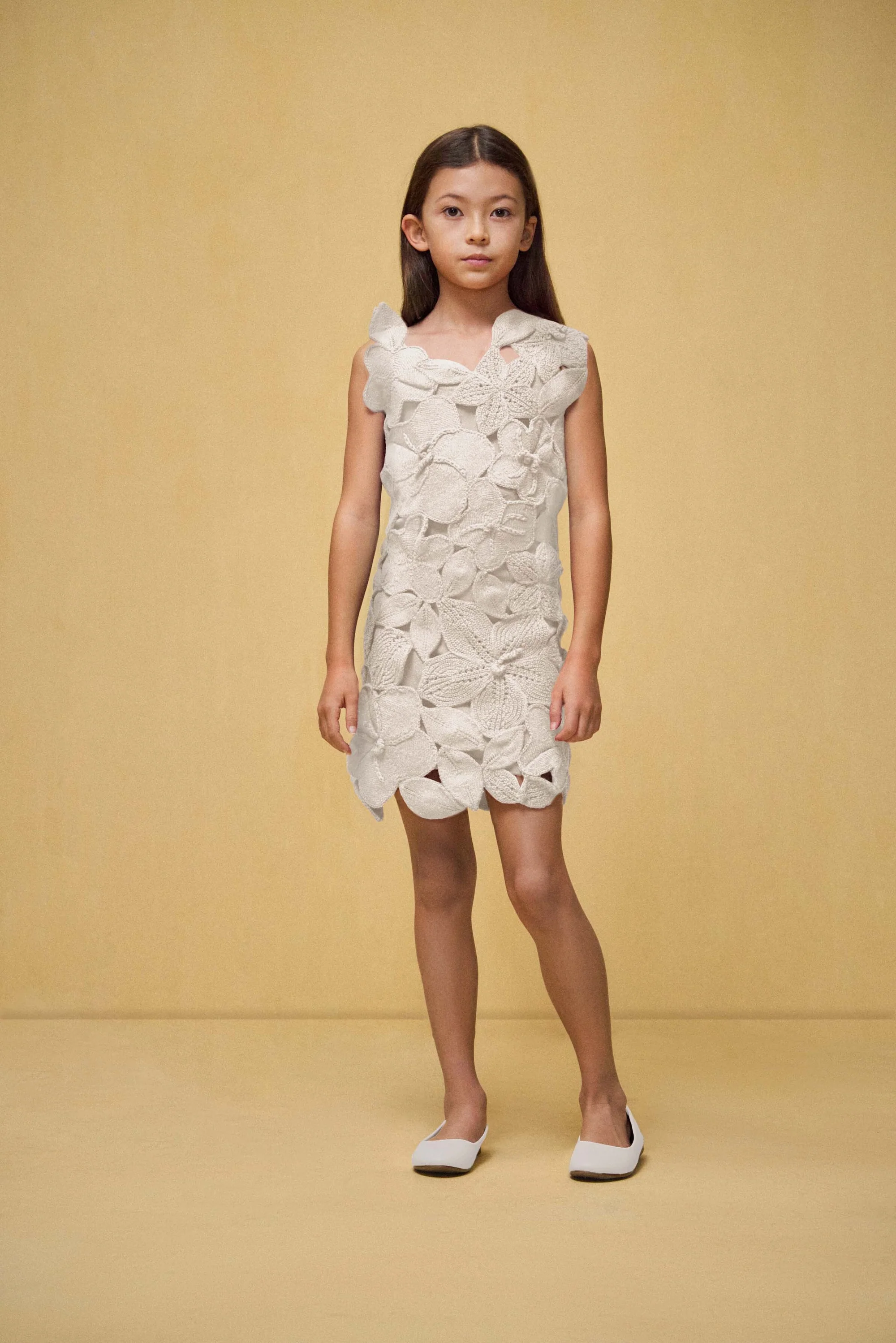 A child model wearing a white floral dress