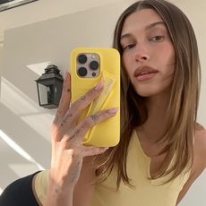 Hailey wears a yellow top and holds the yellow rhode phone case.