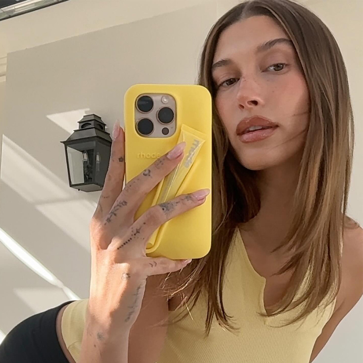 Hailey wears a yellow top and holds the yellow rhode phone case.