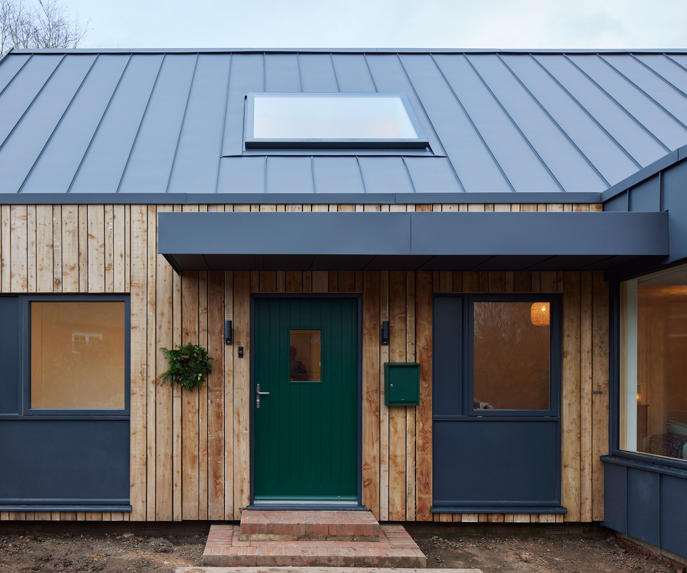 single storey contemporary house with modern flat roof porch and dark green front door