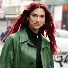 dua lipa, with her hair dyed red, wears a green jacket