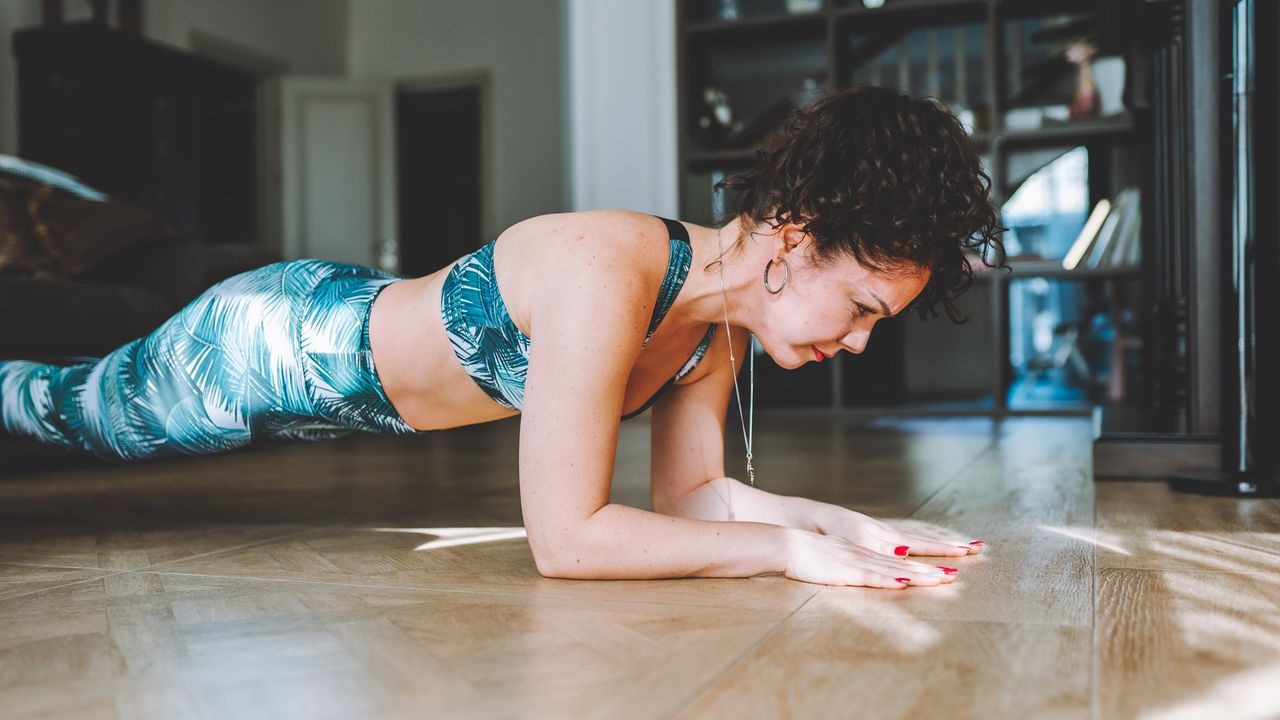 Woman performs a plank in her living room