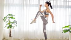Woman raising her knee high as she completes a home workout