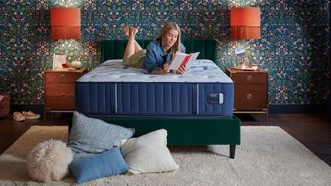 Stearns & Foster Estate Mattress review image shows a woman with blonde hair lying on top of the mattress reading a book