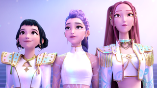 Zoey, Mira and Rumi looking at a crowd proudly while in matching white and gold costumes near the. end of KPop Demon Hunters