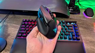 A Razer Basilisk V3 Pro held in the hand above a Razer BlackWidow V4 Pro 75%.