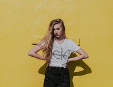 a fashionable woman standing in front of a yellow background