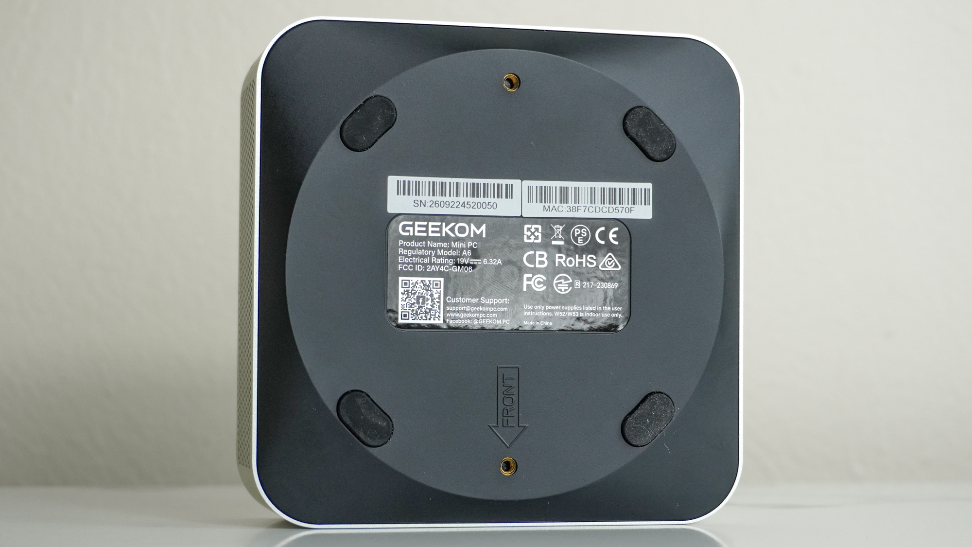 The underside of the Geekom A6 showing its VESA mounting holes and removable rubber feet which cover its case screws