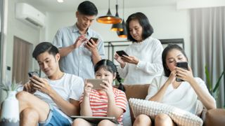 Everyone sitting in sofa and using digital devices in living room insteda of talking to each other