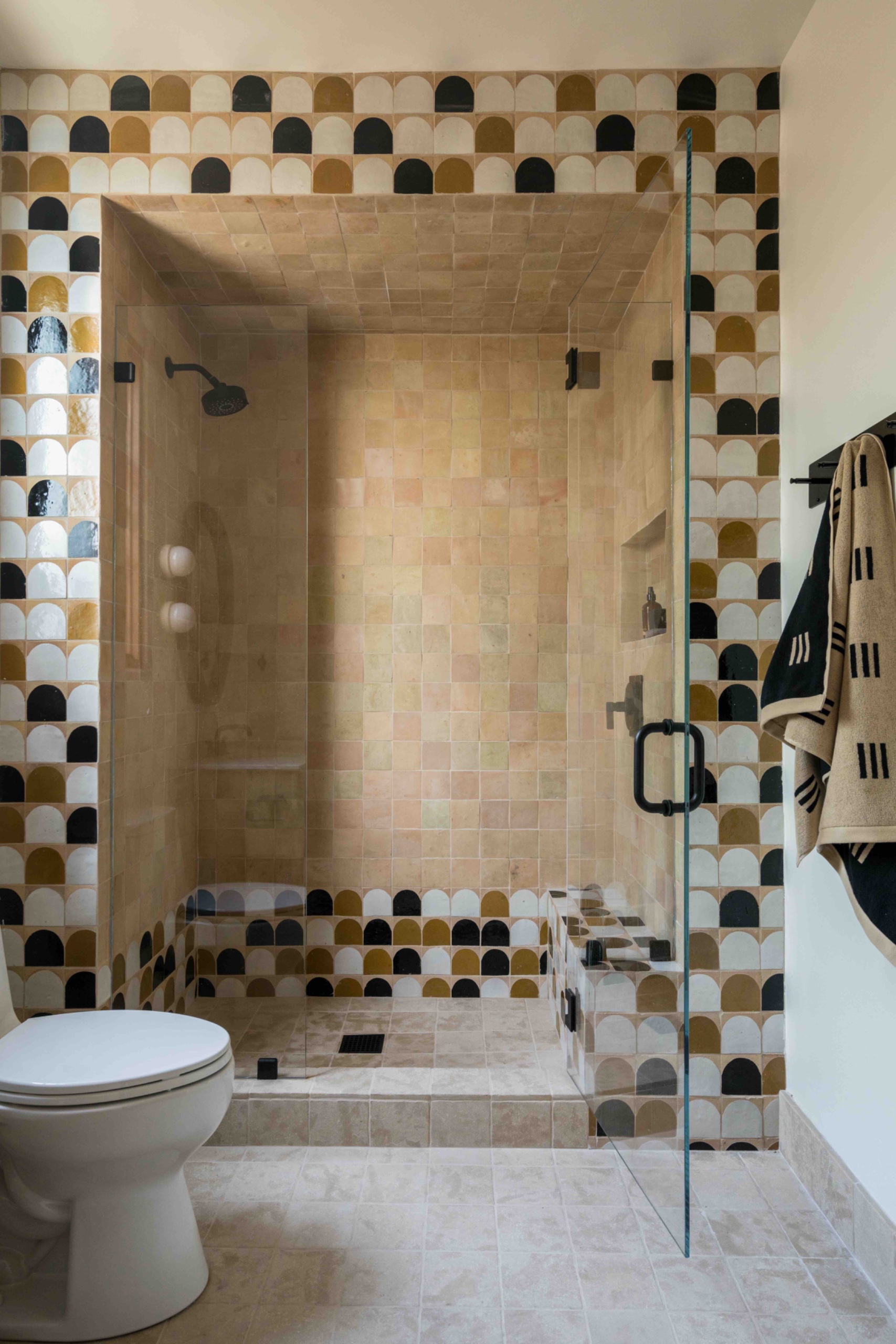 Shower with a raised tiled threshold forming the base of a framed opening, and matching bathroom flooring continuing inside.