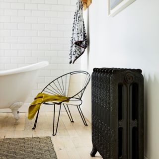 White bathroom with metro tiles, wood floor and black cast iron radiator