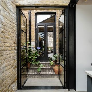 mini courtyard with brick wall black doors and steps
